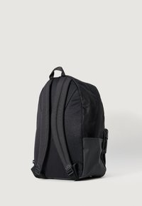Black backpack with padded straps, textured fabric, and a side pocket. The design features a rounded shape and subtle pattern.