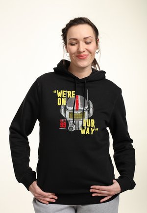 Schwarzer Hoodie mit einem Frontgrafik eines Roboterhelms, gelber Text "WIR SIND UNTERWEGS" und roten Akzenten im Design.