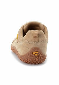 Scarpa in suede beige con suola in gomma testurizzata caratterizzata da motivi triangolari. Accento giallo sul lato e linguetta posteriore in tessuto.