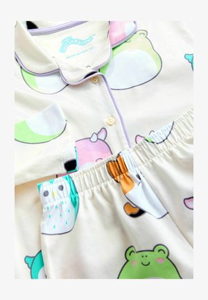 Vaikų kreminės spalvos pižamos su apykakle ir mygtukais, puoštos spalvingais gyvūnų raštais, įskaitant varles, pelėdas ir katę su ragą.