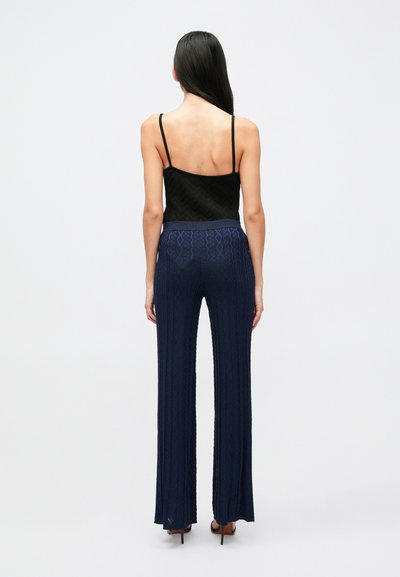 Čierna textúrovaná tielková blúzka s tenkými ramienkami v kombinácii s vysokými modrými nohavicami s rozšírenými nohavicami, vzorované, s rebrovanou textúrou a elastickým pásom.