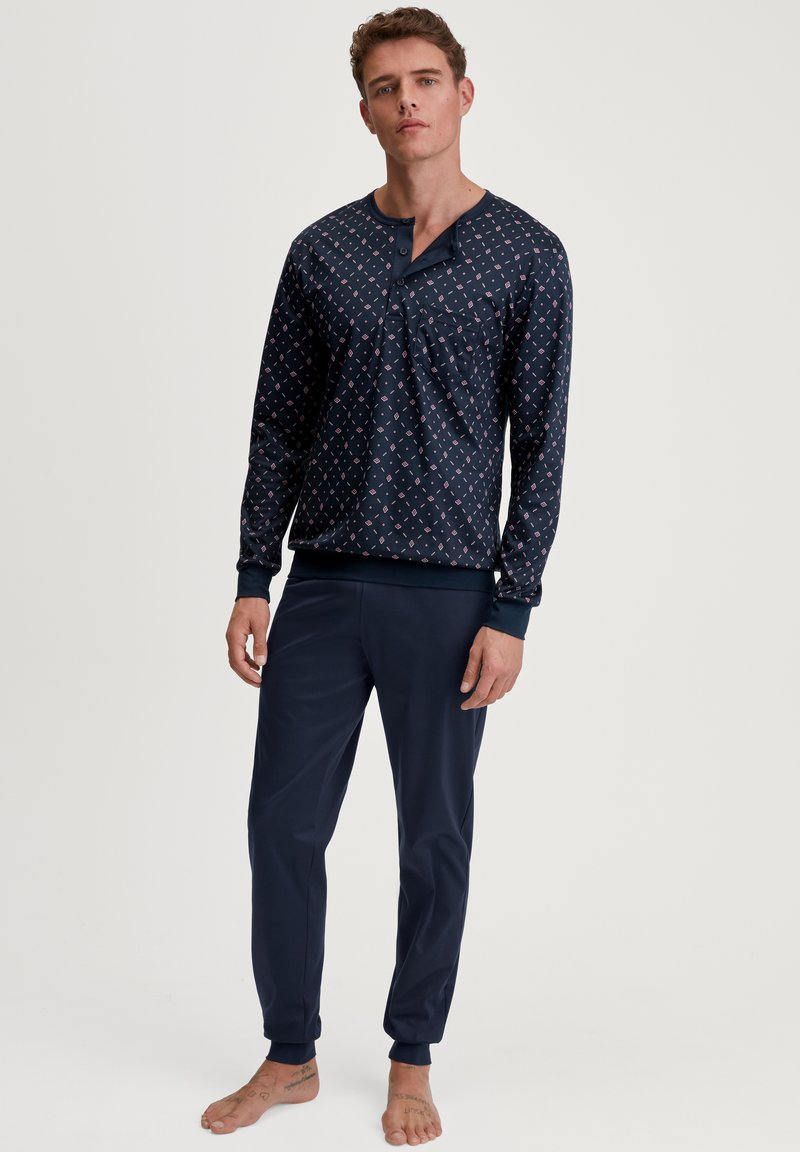 Marineblauw pyjama set met een geblokte lange mouw top met een knoopsluiting en bijpassende taperende broek. Soepele textuur en casual ontwerp.