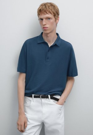 Navy blue polo shirt with a soft texture, short sleeves, three-button placket, paired with white trousers and a black braided belt.