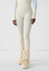 Leggings beige con un diseño texturizado acanalado y cintura alta. Combinados con botas crema acolchadas y con cordones.