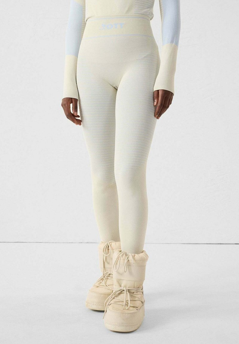 Leggings beige con un diseño texturizado acanalado y cintura alta. Combinados con botas crema acolchadas y con cordones.