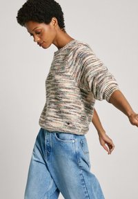 Maglione lavorato a maglia multicolore con scollo rotondo, vestibilità comoda e polsini a coste. Abbinato a jeans chiari a vita alta.