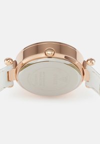 Roosa kullast meeste käekella tagakülg koos valge nahkrihmaga, korona ja kinnitusklambritega valge taustal.