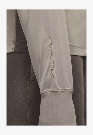 Světle šedé sportovní oblečení s texturovanou tkaninou, s vyšitým nápisem "DRI-FIT" na rukávu a kontrastním tmavě šedým materiálem uvnitř.