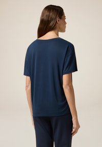 Marineblauwe gebreide t-shirt met een relaxte pasvorm, ronde halslijn en korte mouwen. Gladde textuur en een iets langere achterkant.