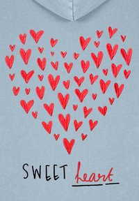 Svetlo modra kapuca z rdečim srcem, ki je sestavljeno iz src v slogu akvarela. Spodaj je napis "SWEET heart" v črni barvi s stilizirano podčrtano vrstico.