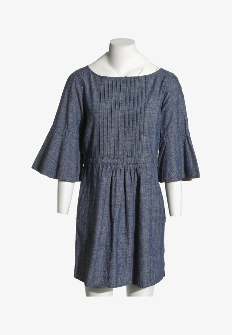Robe bleu denim avec devant plissé, encolure bateau et manches trois-quarts évasées, présentée sur un buste de mannequin blanc.