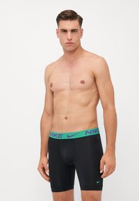 Fekete boxer alsónemű zöld és lila mintás der�ékrésszel, elöl Nike logóval és kényelmes, testhezálló kialakítással.