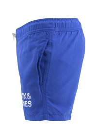 Bañador azul con cinturilla elástica, bolsillos laterales y texto de logo en blanco. Fabricado con tejido ligero, de diseño corto y casual.