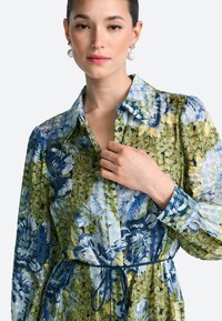 Kvetinové šaty na zapínanie na gombíky s vzorom v zelenej a modrej farbe, ľahkou textúrou, dlhými rukávmi a zúženým pásom s detailom na zaväzovanie.