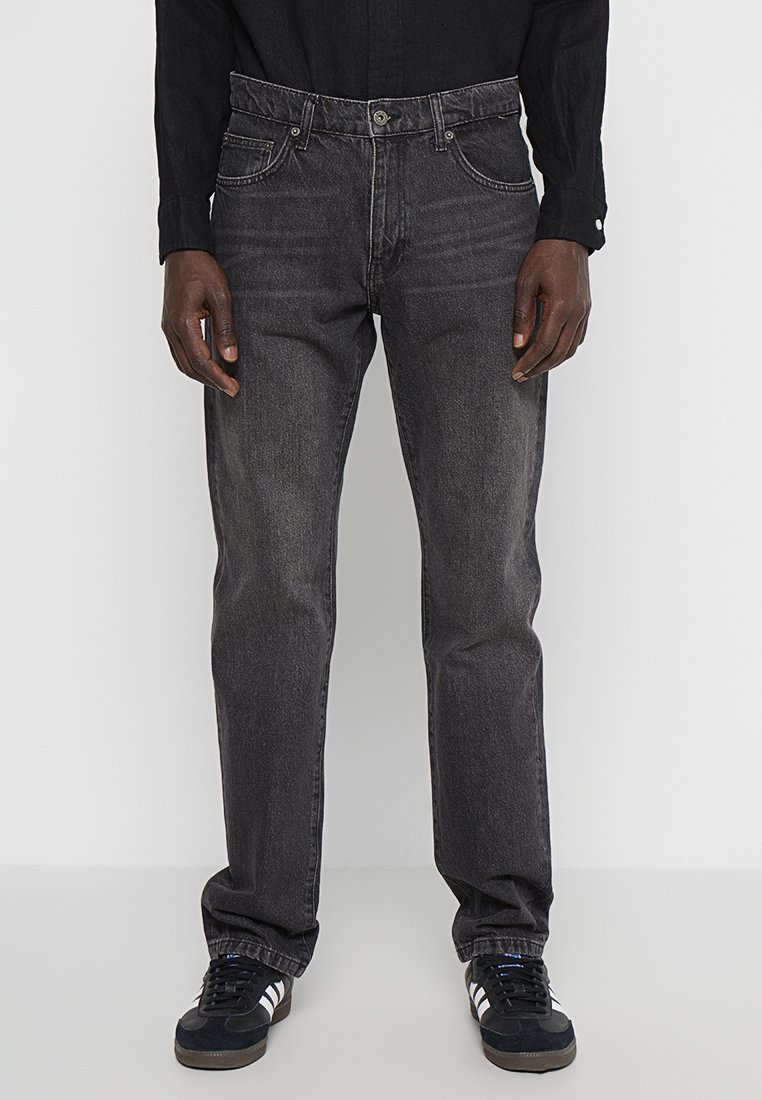 Zwarte denim jeans met een rechte snit, vijf zakken, subtiele vervaging en contrasterende stiksels. Gecombineerd met zwart-witte sneakers.