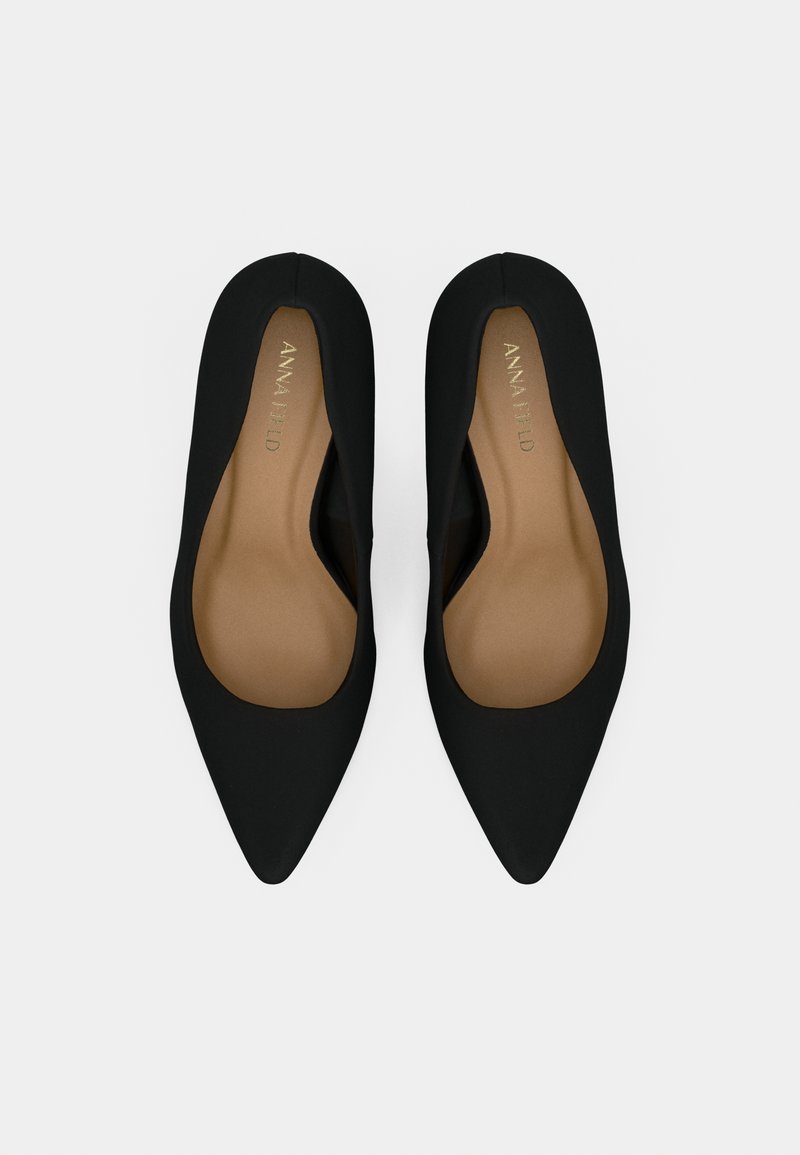 Une paire de ballerines noires à bout pointu avec des semelles intérieures beiges et la marque "ANNA FIELD" à l'intérieur, présentée de dessus sur un fond blanc.