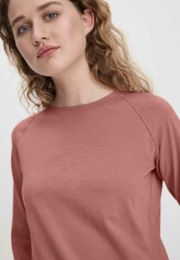Maglia con maniche raglan in morbido tessuto color rosa polveroso. Leggera, con una texture liscia, dal design semplice e scollatura rotonda.