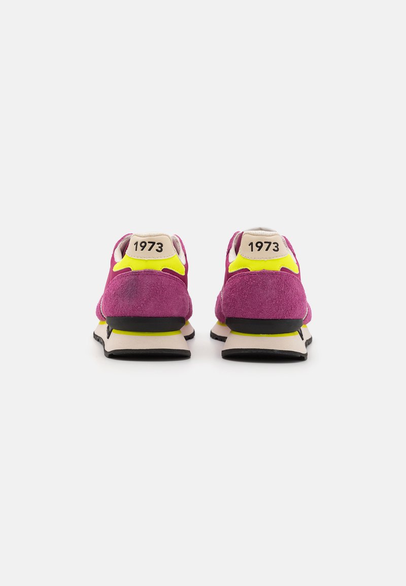Lila Wildlederschuhe mit gelben Akzenten, schwarzer Laufsohle und beigem Fersentag mit dem Text "1973". Klassisches Design mit gepolsterter Unterstützung.