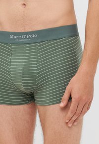 Boxer shorts verts rayés avec une texture douce. La ceinture élastique arbore le logo "Marc O'Polo" en texte gris.