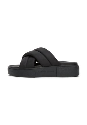 Sort slip-on sandal med tykke krydsede polstrede tekstilremme og en tekstureret sål med Tommy Jeans mærkat på siden.