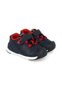Zapatillas atléticas de color azul marino con acentos rojos; parte superior de malla, correas de velcro, puntera negra y entresuela blanca con suela texturizada.