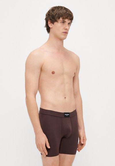 Καφέ μποξέρ σορτς από λείο, ελαστικό ύφασμα. Διαθέτει μαλακή ελαστική μέση με μικρή ετικέτα λογότυπου μπροστά.