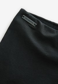 Crni tekstil s glatkom teksturom i suptilnim sjajem, s metalnom oznakom na kojoj je ugravirano "ALLSAINTS."