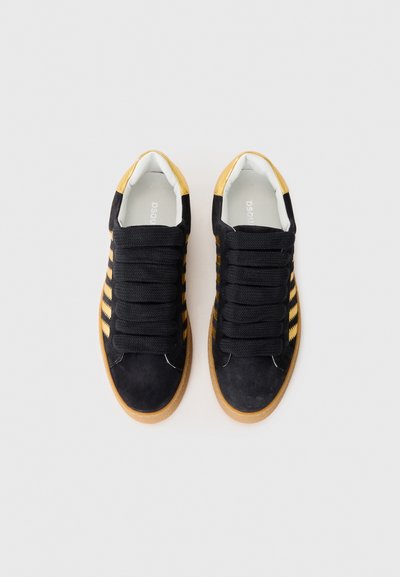 Black suede sneakers with yellow stripes, rubber gum sole, and thick black laces. Includes a cushioned interior for comfort.