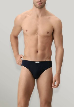 Costumi da bagno neri da uomo realizzati in tessuto morbido, con design a vita bassa e una piccola etichetta con logo sulla cintura.
