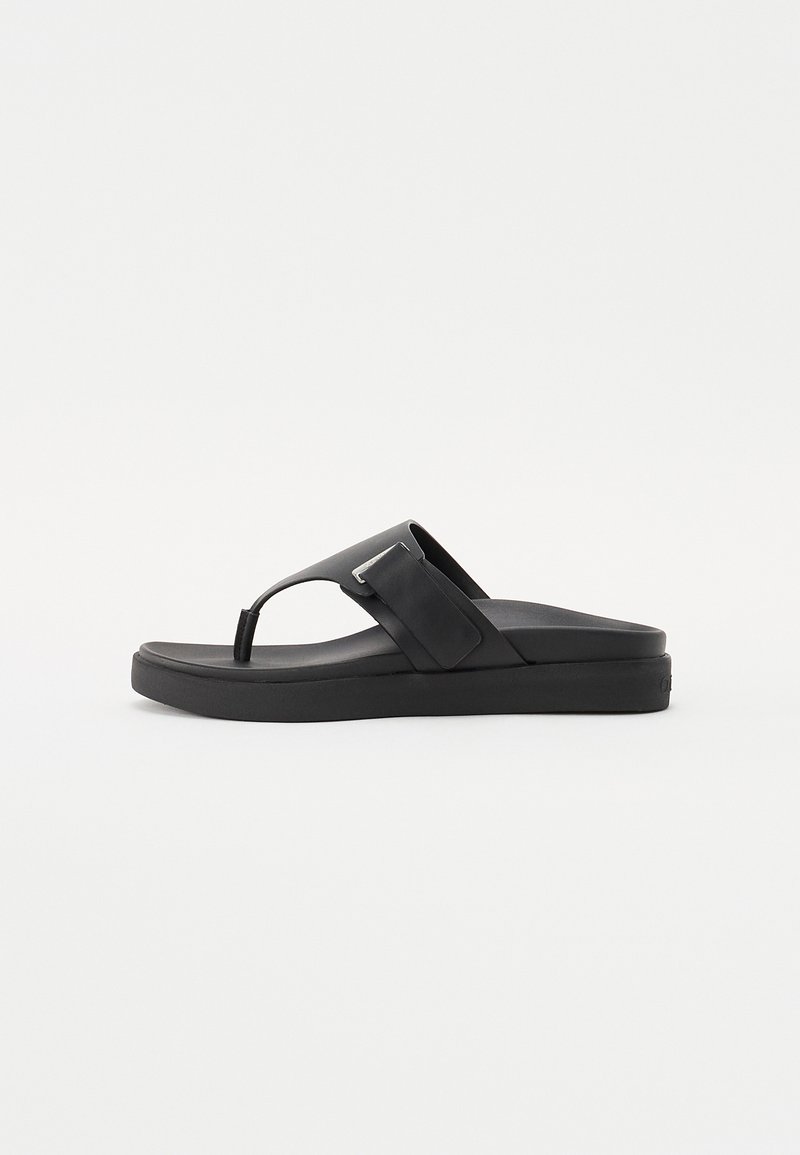 Svart flip-flop sandal med en bred stropp som har en rektangulær detalj, flat såledesign, og polstret mellomsåle for komfort.