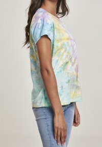 Korte mouwen tie-dye T-shirt in pastelkleuren van blauw, geel en paars; ontspannen pasvorm; zachte katoenmaterialen; ronde halslijn en zijsplitten.