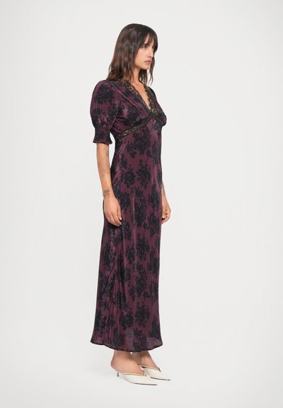 Long, purple floral dress with short puff sleeves, lace trim, and a flowing design. Smooth fabric with a slight shine and side slit.