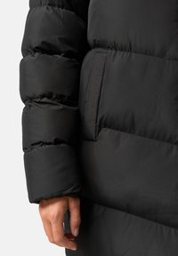 Giubbotto imbottito nero con design trapuntato, caratterizzato da una texture liscia, una tasca laterale e un polsino aderente alla manica.