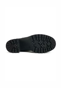 Black rubber shoe sole with deep treads and floral patterns for traction. Features raised sections and a textured surface.