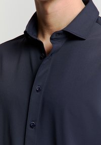Marineblauw overhemd met knopen, een gestructureerde kraag, een gladde textuur en donkere knopen. Het heeft een slim-fit ontwerp en verhoogde stiksels.
