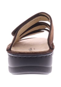 Bruine leren slidesandalen met drie banden, platte zwarte platformzool en een met textuur bedekte voetbed. Stikdetails langs de randen.