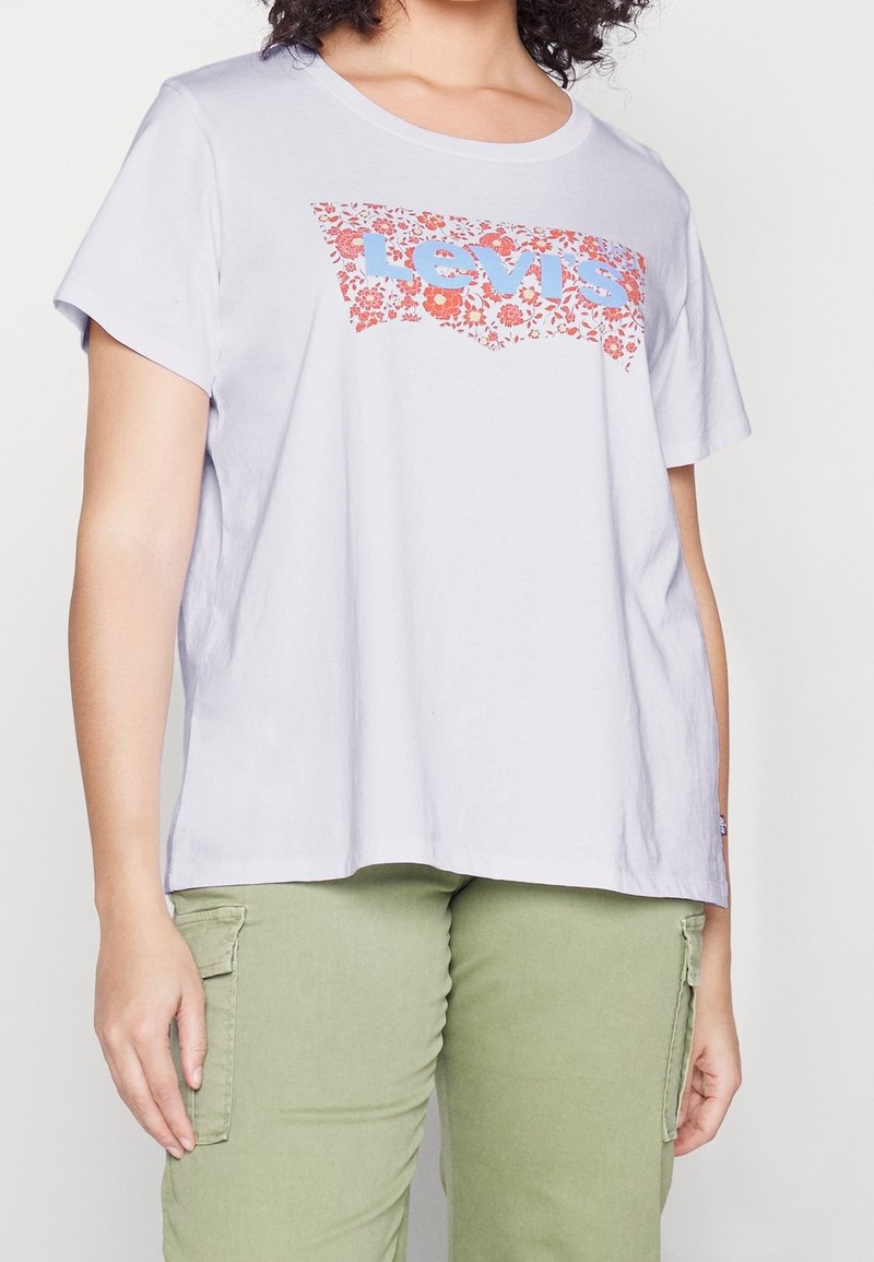 T-shirt lilas à manches courtes avec col rond, arborant un logo Levi's floral rouge et bleu. Matière en coton doux avec une coupe ample.
