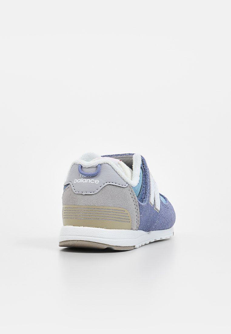 Lila und graue Sportschuhe mit einem Obermaterial aus Wildleder, weißen Akzenten, einem gepolsterten Schaft und einer strukturierten Sohle. Die Rückansicht hebt das Logo hervor.