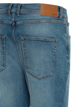 Jasnoniebieskie dżinsy denimowe o gładkiej fakturze, wyposażone w dwie tylne kieszenie, kontrastujące pomarańczowe przeszycia oraz jasnobrązową skórzaną etykietę na pasie.