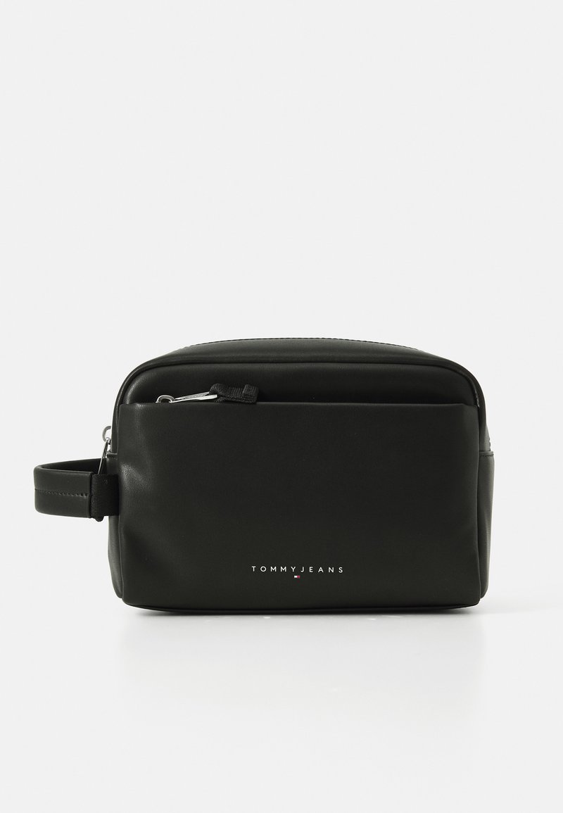 Borsa da toilette in pelle nera con forma rettangolare, chiusura con zip, manico laterale e logo "TOMMY JEANS" in rilievo sul davanti.