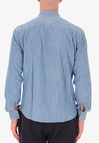 Camicia in denim azzurro chiaro con maniche lunghe, colletto classico e polsini abbottonati. Presenta un orlo curvo e una finitura tessuta e testurizzata.