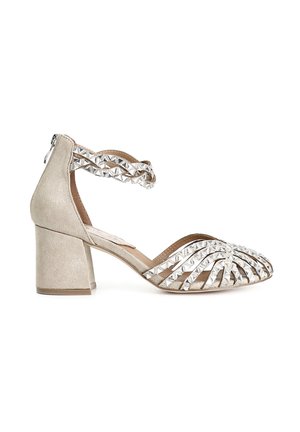 Sandal con tacco in suede beige, dotata di tacco a blocco, con una fascia incrociata decorata con borchie metalliche a piramide e un design open-toe.