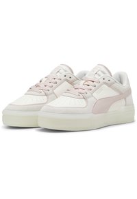 Ett par låga Puma-sneakers i off-white och ljusrosa med perforerat tåbox och tjocka genomskinliga sulor, visade sida vid sida.
