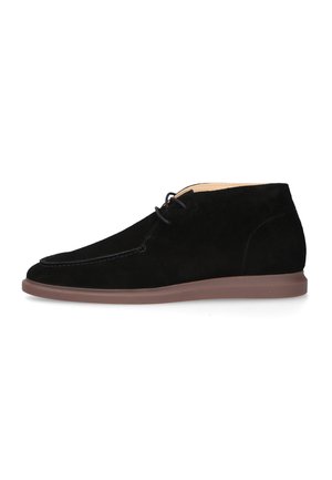 Scarpa casual in camoscio nero alta alla caviglia con lacci frontali e suola in gomma marrone, mostrata dal lato esterno su sfondo bianco.