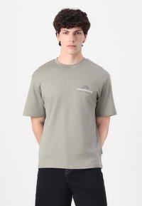 Lys grå kortærmet t-shirt lavet af blød bomuld, med et lille "ATHLETIC CLUB" grafisk print og design med rund hals.