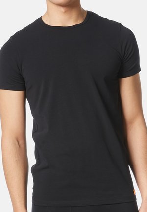 T-shirt noir à manches courtes et col rond en coton doux, avec une coupe ajustée et une petite étiquette de marque orange près de l'ourlet.