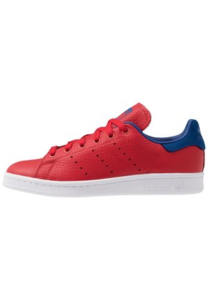 Rød Adidas Stan Smith sneaker med blå hælkappe og hvid sål, vist fra siden med snørebånd og perforerede striber.