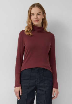 Bordeauxrode turtleneck top van rekbare stof, lange mouwen, aansluitend ontwerp, effen textuur, gecombineerd met donkere denim broek met verticale naden.