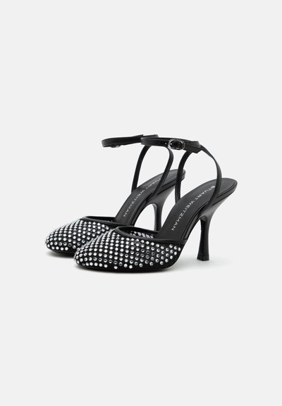 Chaussures à talons hauts noires avec bride arrière, lanières de cheville, bouts pointus et ornements scintillants en strass sur le devant.
