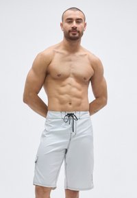 Férfi szürke úszónadrág fekete varrással, zsinóros derékrésszel és oldalzseb részlettel. Könnyű, gyorsan száradó anyagból készült.